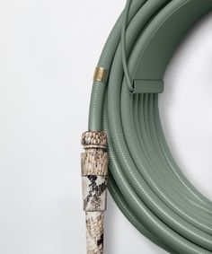 a green hose connected to a white wall with a cork top on the end next to it