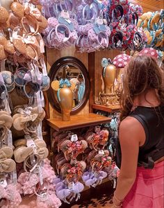 a woman standing in front of a store filled with lots of headbands and hair accessories