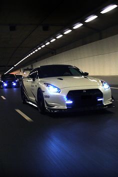 two sports cars driving through a tunnel at night