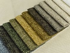 a row of different colored rugs on top of a white bed sheet with no sheets