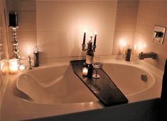 a bath tub with candles and wine in it