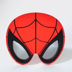 a close up of a spider man mask on a white surface with black eyes and an orange background