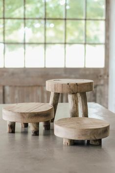 two wooden stools sitting next to each other on top of a table in front of a window