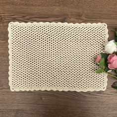 a white placemat with flowers on top of it next to a wooden tablecloth