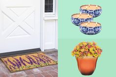 three pots with flowers and candles on them next to a door mat that has been placed in front of a white door