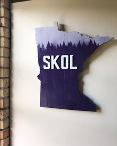 a piece of wood with the word skol painted on it in white and purple