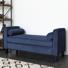 a blue couch sitting on top of a rug next to a book shelf filled with books