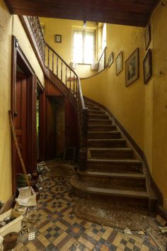 an old staircase in the middle of a room with tile flooring and peeling paint on the walls