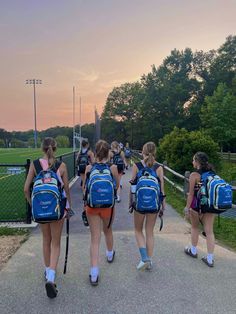 the girls are walking down the path with their backpacks on and back to school