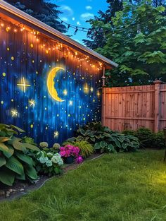 a backyard with lights on the side of it and flowers in the grass near by