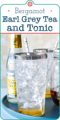 two glasses filled with tea and ice sitting on top of a blue tray next to bottles