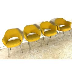 four yellow chairs lined up against a white wall