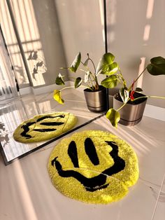 a smiley face rug is on the floor next to a mirror and potted plants