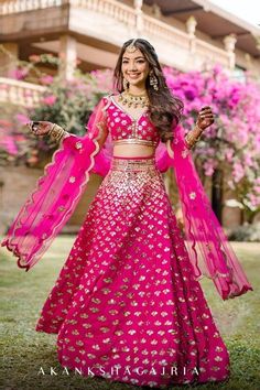 a woman in a pink and gold lehenga is posing for the camera with her arms outstretched