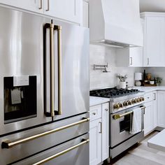 a kitchen with white cabinets and stainless steel appliances, including an oven, range, microwave, stove top and refrigerator