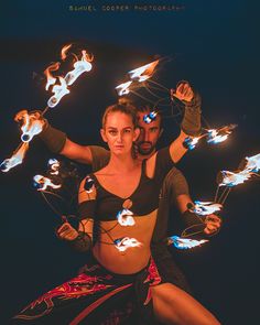 a man and woman are dancing with their hands in the air while surrounded by fire