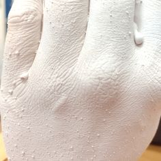 a close up of a person's hand with white paint on it and water droplets all over the palm