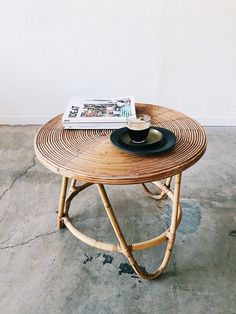 a wicker table with a magazine on it and a black plate sitting on top