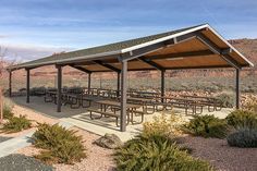 a covered picnic area in the desert with tables and benches on it's side