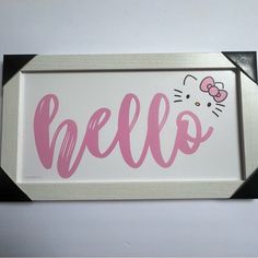 a hello kitty sign hanging on the wall next to a white and black framed object