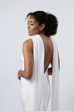 a woman in a white dress with her back turned to the camera and wearing an open neckline