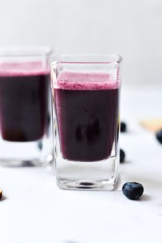 two glasses filled with blueberry smoothie on top of a table