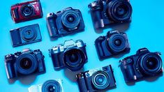 many different types of digital cameras on a blue surface with one camera facing the camera