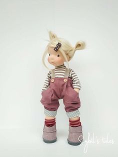 a doll with blonde hair and overalls is standing on a white background wearing boots