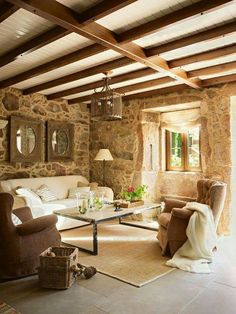 a living room filled with furniture and stone walls