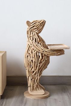 a sculpture made out of branches sitting on top of a wooden table next to a white wall