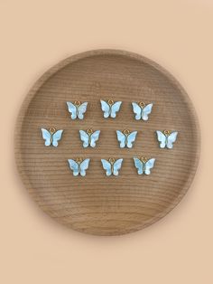 blue butterflies are arranged in a circle on a wooden plate with gold earring hooks