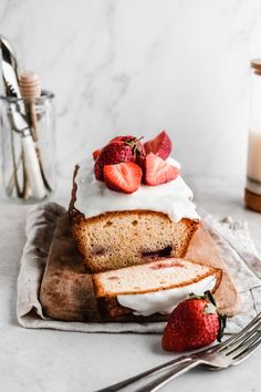 slices of cake with whipped cream and strawberries on top, sitting on a cutting board