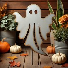 a wooden cutout of a ghost surrounded by pumpkins