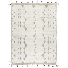 a white and grey rug with tassels on the bottom, in front of a white background