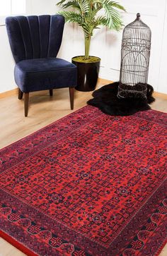 a large red rug in the middle of a room with two chairs and a birdcage