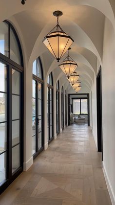 a long hallway with many windows and lights on the ceiling, along with wooden flooring