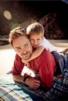 a man and his son are laying on the beach