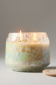 a lit candle sitting on top of a table next to a wooden spoon and plate