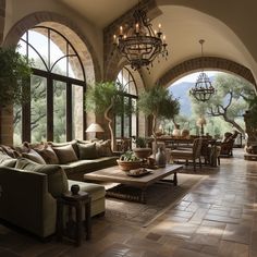 a living room filled with lots of furniture next to large arched windows on top of a stone wall