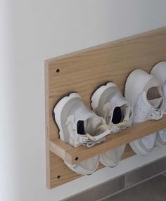 three pairs of white shoes are on a wooden shelf with two holes in the middle