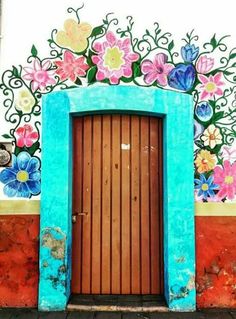 an entrance to a building with flowers painted on the wall and doors in different colors