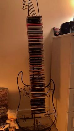 a stack of cds sitting on top of a metal stand next to a white dresser