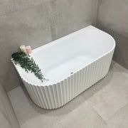 a white bath tub sitting in a bathroom next to a toilet paper roll and flower