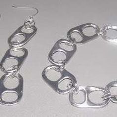 a pair of silver bracelets and earrings on a white table with an earring