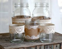 two mason jars with lace on them are sitting on a table