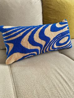 a blue and white pillow sitting on top of a couch