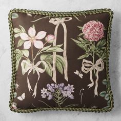 a brown pillow with pink flowers and green trimmings on the front, sitting on a marble surface