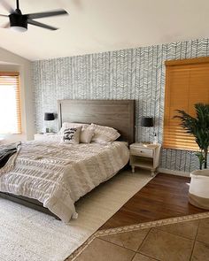 a bedroom with a bed, nightstands and ceiling fan in the middle of it