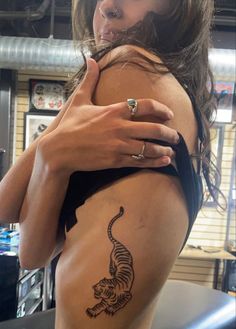 a woman with a tiger tattoo on her side holding onto the back of her body