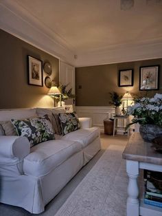 a living room filled with furniture and pictures on the wall next to a coffee table